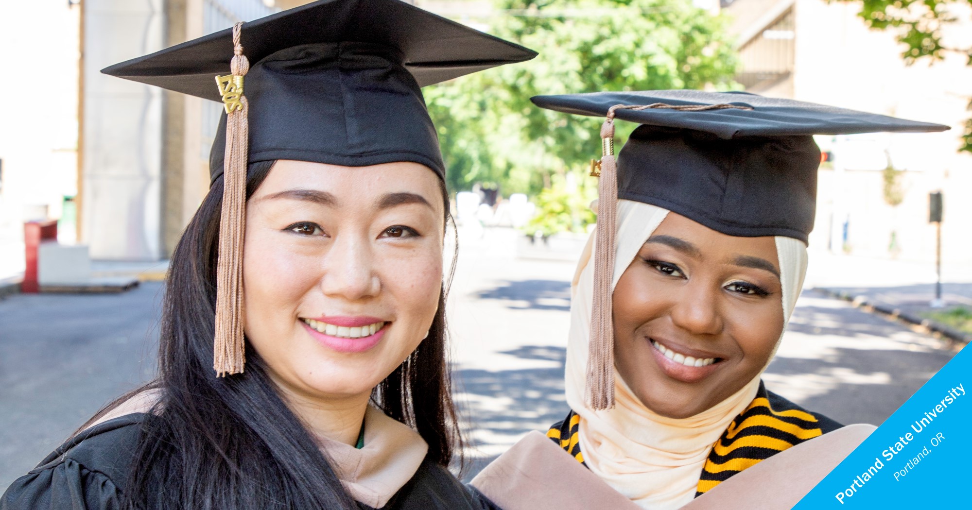 Two smiling graduates of Portland State University