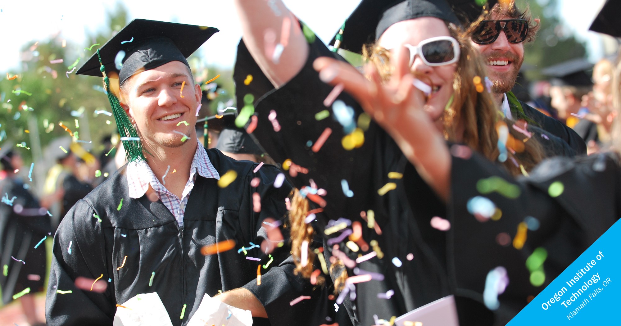 Smiling graduates of OIT tossing confetti